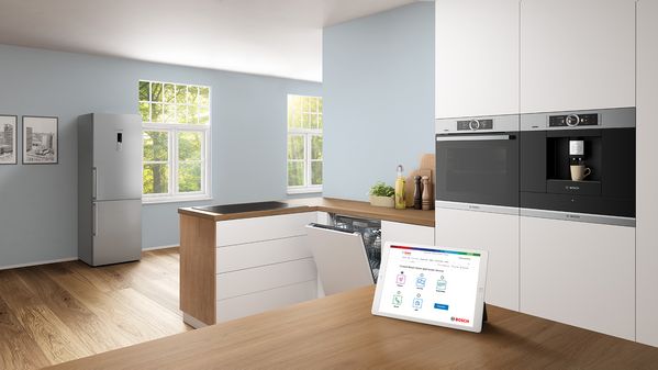 Tablette montrant la page de contact de Bosch sur un comptoir en bois dans une cuisine blanche.