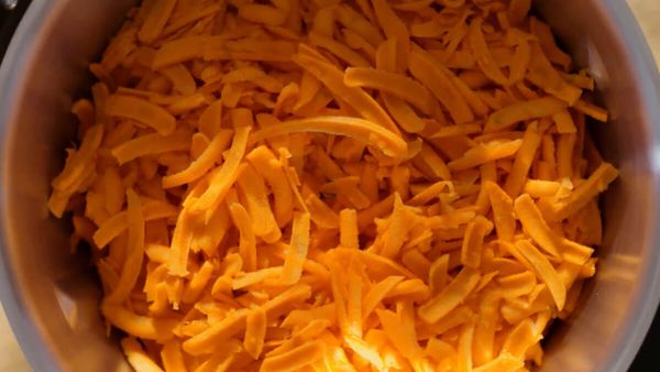 Top view of a cookit in which carrots are chopped.