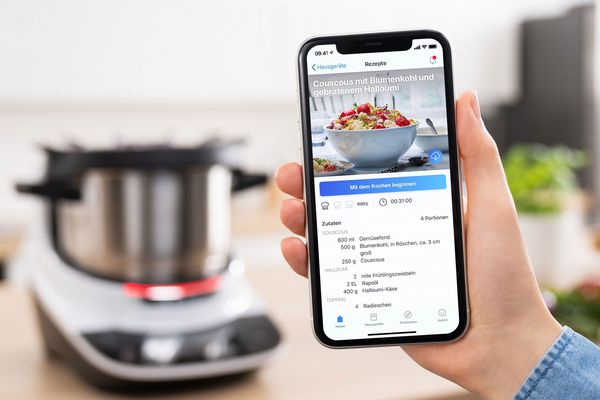 The Home Connect App opened on a smartphone with the Cookit in the back. 