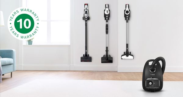 Black Bosch vacuum cleaner on a white rug. To the left, the 10 year warranty icon stands for the free extended motor warranty.