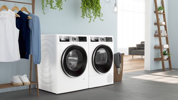 Bosch Wärmepumpentrockner in einer modernen Waschküche mit Wäscheleiter, Kleiderständer und Pflanzen. 