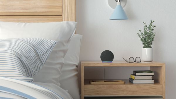 The Amazon Echo standing on a bed shelf next to a cozy bed.