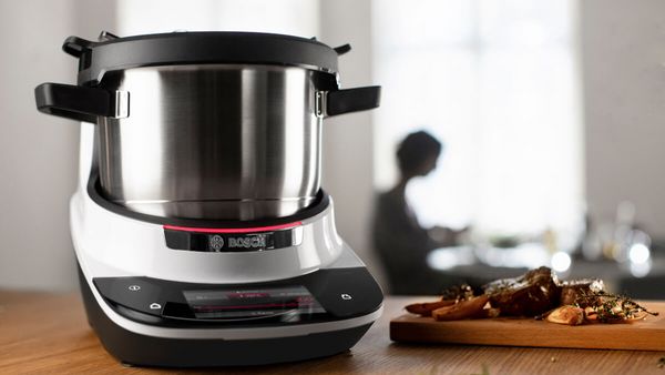 The Bosch Cookit standing on a kitchen shelf with a person in the background.