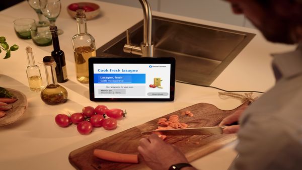 A man skillfully slicing vegetables on a tablet, showcasing modern cooking techniques in front of tablet with voice control