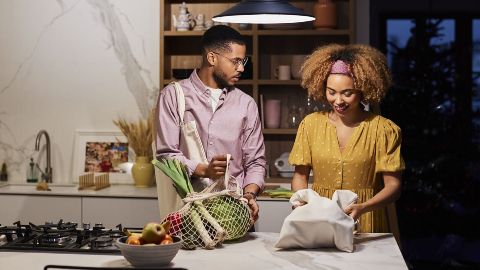 Couple in kitchen with groceries.