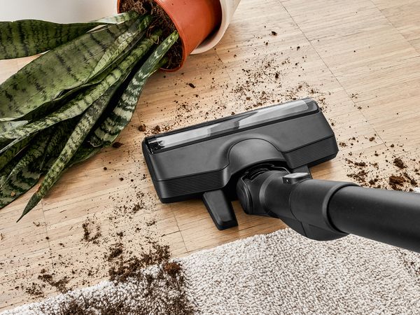 Cordless vacuum cleaner Unlimted 8 powerfully cleans up dirt from a tipped over house plant.