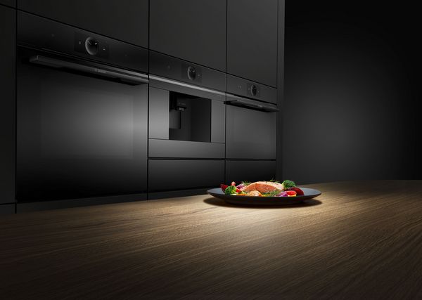 Serie 8 ovens in een keuken. Op het werkblad staat een bord met zalm en groenten.
