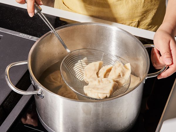 Scooping dumplings out of boiling pot