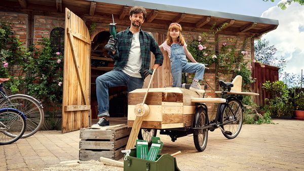 Stolzer Vater und Tochter präsentieren ihr umgebautes Lastenrad in Form eines Flugzeuges.