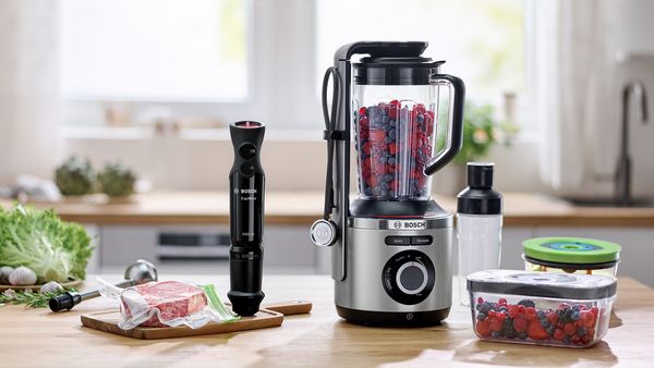 Bosch vacuum-sealing hand blender and blender on a kitchen worktop next to compatible containers.