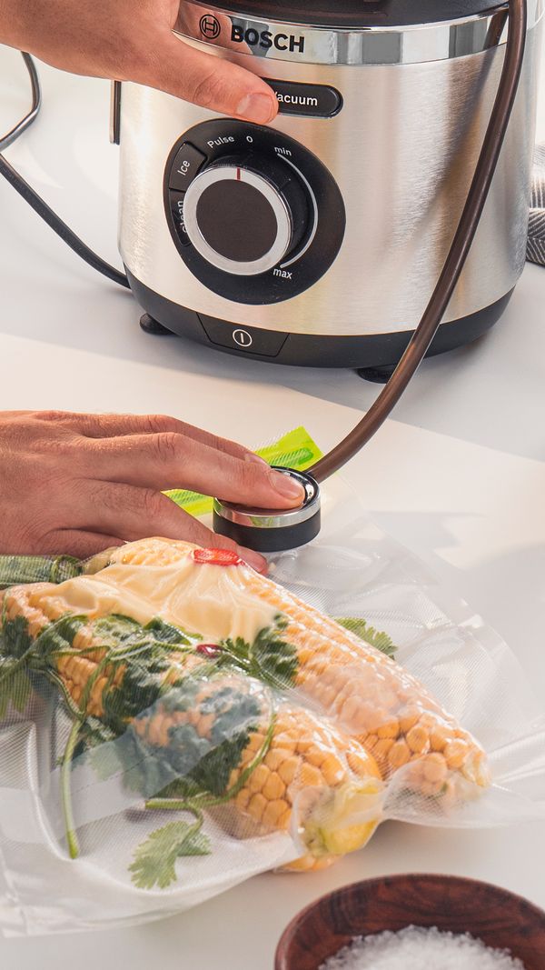 A person pressing the button to remove air and vacuum seal food.