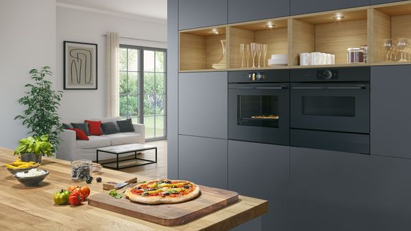 Twee ovens en een koffiemachine ingebouwd in een witte kast in een witte keuken.