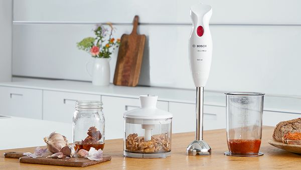 A CleverMixx hand blender clustered with its accessories on a counter in a bright, white kitchen.