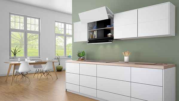 Cocina moderna con armarios blancos, encimera de madera y grandes ventanales con vistas a la vegetación, de diseño minimalista.