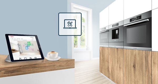 Modern wooden kitchen with appliances, a blue service assistant icon and there is a tablet and a coffee cup on the worktop.