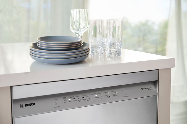 Bosch dishwasher closed with clean dishes on counter