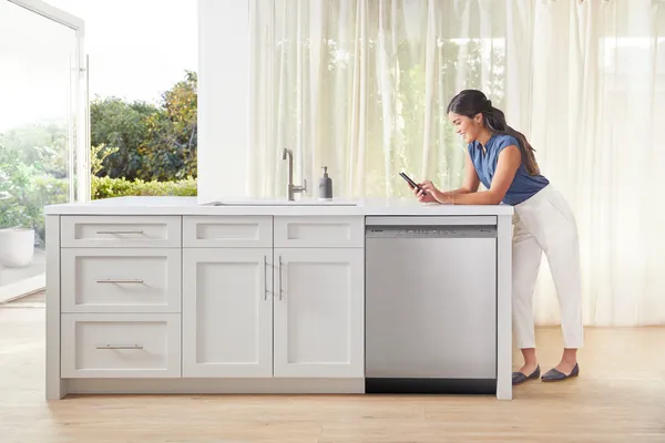 woman bent over countertop on home connect app with bosch dishwasher