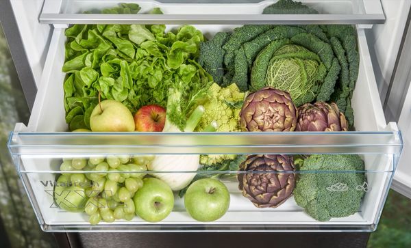 Top view of VitaFresh XXL drawer open with mainly green fruits and vegetables inside.