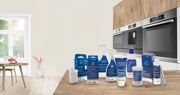 Different cleaning and care products on a wooden kitchen countertop.