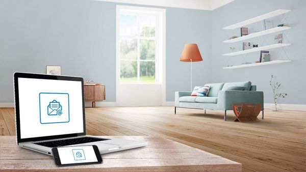 Salon avec un ordinateur portable et un smartphone sur une table montrant une icône de newsletter bleue.