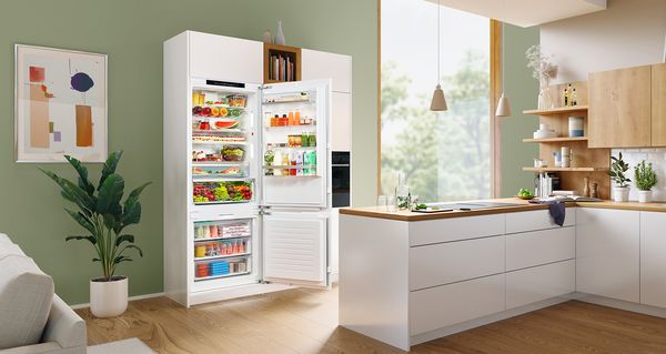 Totaal zicht op een keuken/eetruimte in een mooie moderne inbouwkeuken met een geopende XXL koel-vriescombinatie.