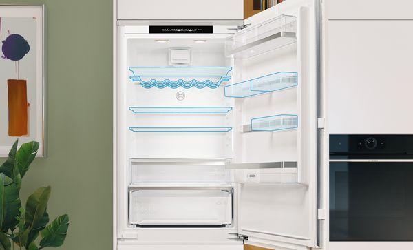 Opened and empty integrated XXL fridge freezer. Flexible shelves and adjustable door shelves are highlighted in bluish color.
