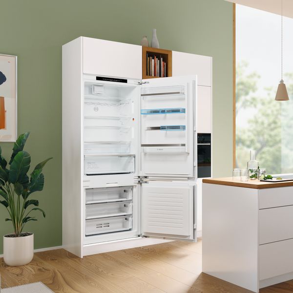 Réfrigérateur-congélateur XXL intégré ouvert et vide. Étagères flexibles et étagères de porte ajustables sont de couleur bleuâtre.
