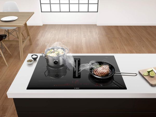 Moderne open keuken met inbouwapparaten op borsthoogte en een pan op het kookeiland