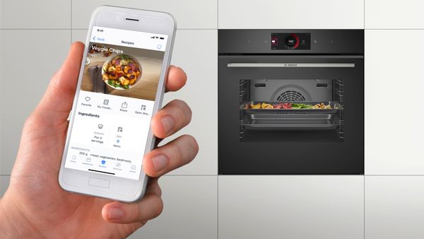 A person holding an iPhone next to an oven, using a cooking app.