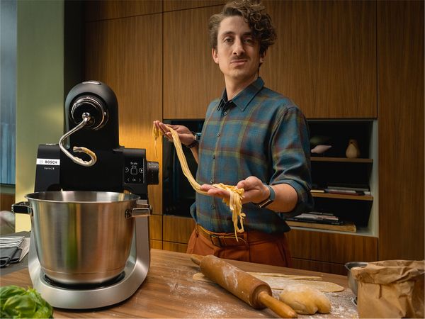 Serie 6 kjøkkenmaskin på en kjøkkenbenk. En mann viser frem en perfekt pastadeig.
