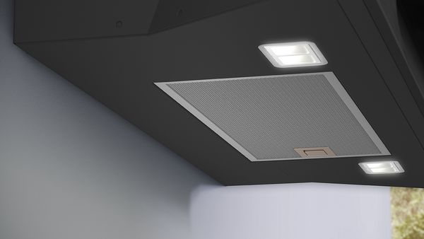 Nærbillede af det nederste af en skrå emhætte med LED-belysning.