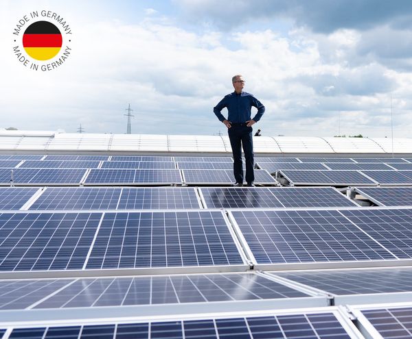 Ein Mann steht auf einer großen Photovoltaikanlage; Logo Made in Germany