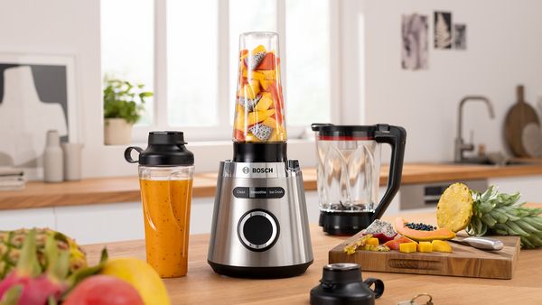 VitaPower Standmixer mit Obststücken steht neben einer ToGo-Flasche mit einem Smoothie auf einer Küchenarbeitsplatte.