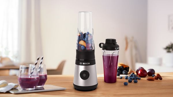 MiniBlender next to ToGo Bottle filled with smoothie and two glasses containing the same drink.
