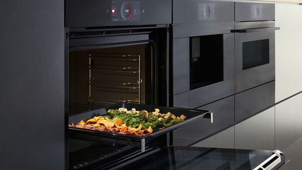 Four noir avec porte ouverte et plaque de légumes grillés