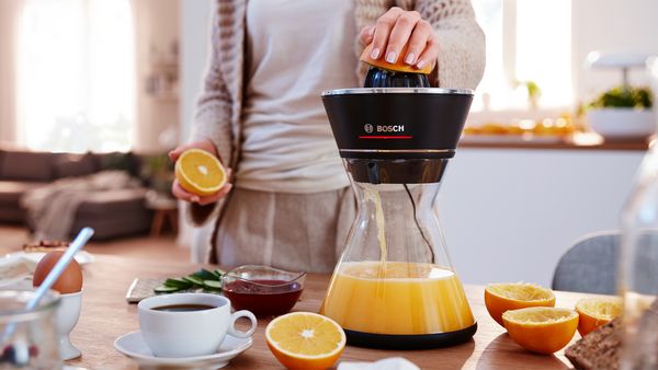 Bosch citrus press VitaStyle with glass jug standing on a kitchen worktop.