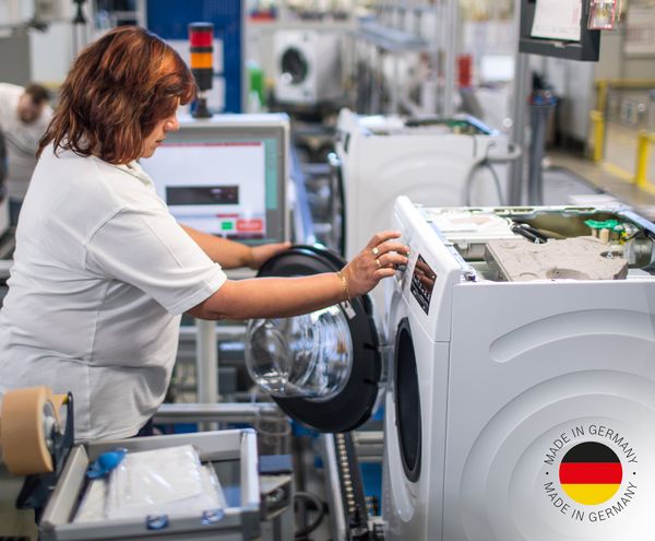Eine Bosch-Mitarbeiterin prüft eine Bosch Waschmaschine; Made in Germany-Logo