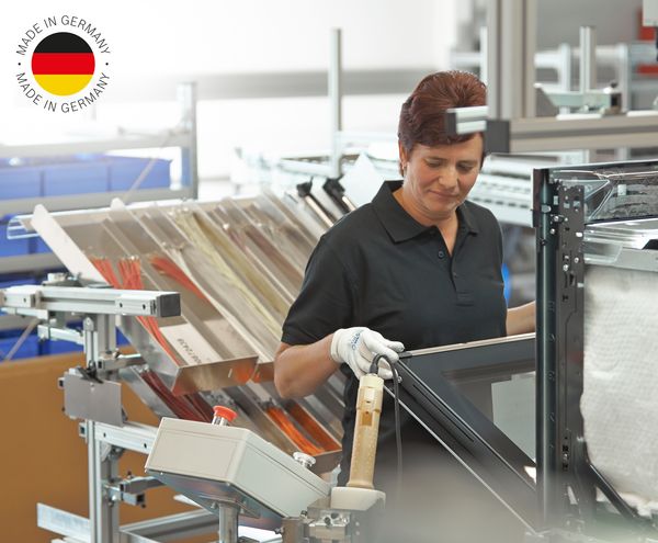 Mitarbeiterin prüft einen Einbaubackofen von Bosch; Made in Germany-Logo