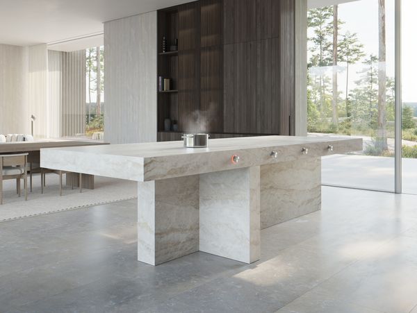 Large bright luxury open-plan kitchen and dining room with an expansive kitchen island containing a unseen induction cooktop heating a kettle