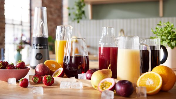 Auf einer Küchenarbeitsplatte befinden sich verschiedene Säfte und Früchte neben einem Bosch Mixer.