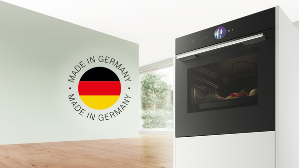 Bosch Backofen mit zubereiteten Speisen im Garraum neben einem &bdquo;Made in Germany&ldquo;-Siegel; hebt die hochwertige, in Deutschland gefertigte Backofentechnik hervor.