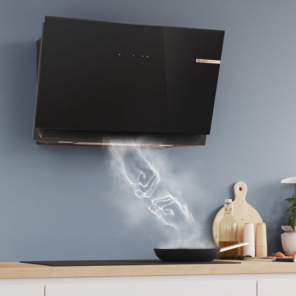 Steam clouds rising from a frying pan on a hob towards an inclined cooker hood form two hands meeting in a fist bump.