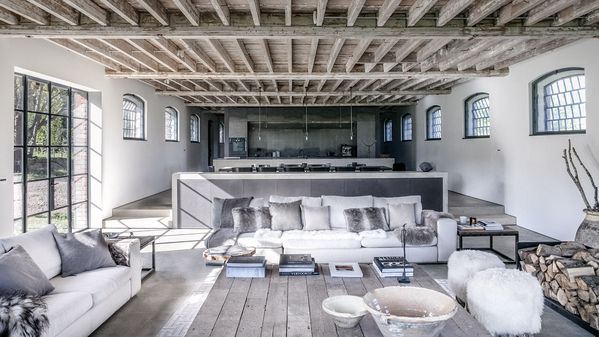 View of the long open plan living space of Noble Barn, showing the living room and kitchen featuring Gaggenau appliances.