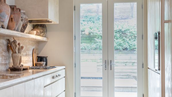 Galley kitchen with pared-back tones fitted with Gaggenau appliances and patio doors leading to a garden