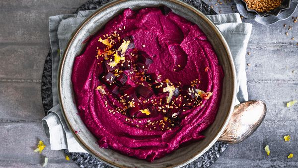 Beetroot hummus in a ceramic bowl shot from above.