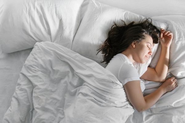 Donna che dorme in un letto con lenzuola bianche