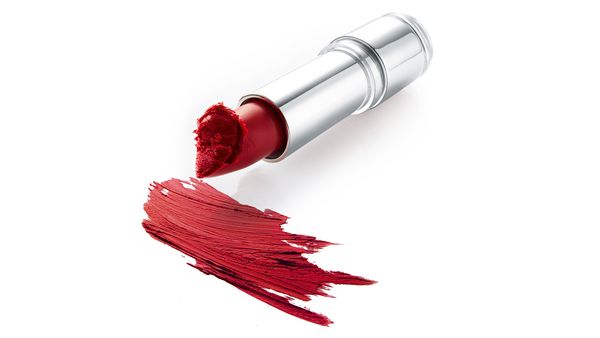 Ein offener roter Lippenstift und Schmierspuren auf einer weißen Fläche.