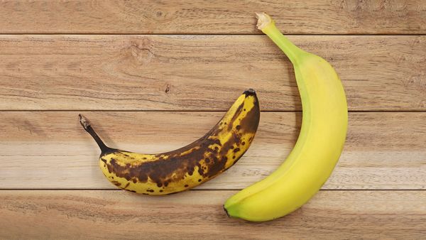 Svetlo rumena banana poleg bolj zrele rjave banane s kožo.