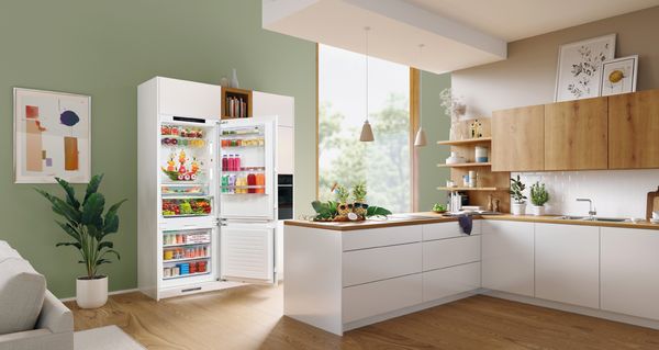 Vista general de una zona de cocina-comedor en una hermosa cocina moderna integrable con un frigorífico XXL abierto.