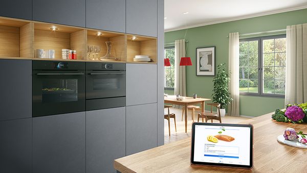 En iPad på en kjøkkenøy viser en sitronkake. Integrerte ovner i bakgrunnen setter scenen.